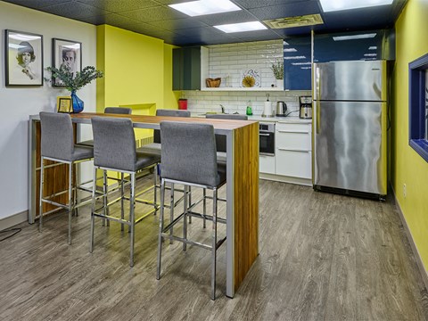 a kitchen with a bar and chairs and a refrigerator