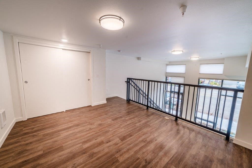 an empty living room with a balcony and wood flooring