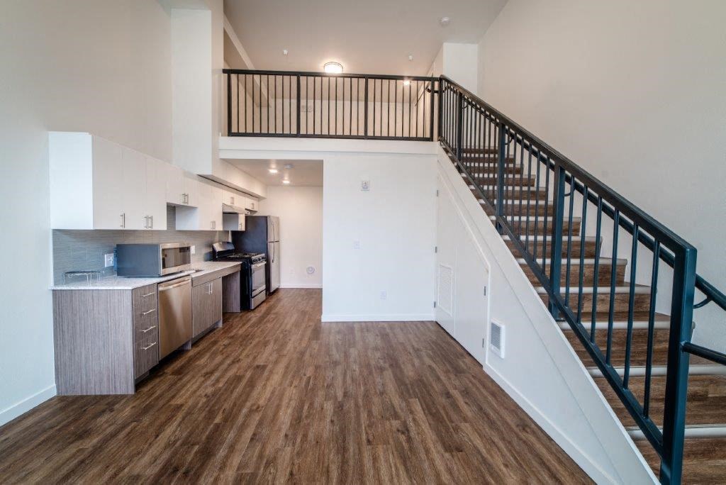 a living room with a staircase and a kitchen in a house