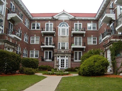 a red brick apartment building with a sidewalk and grass