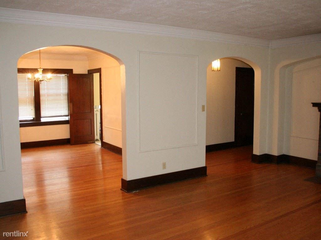 an empty living room with wood floors and white walls