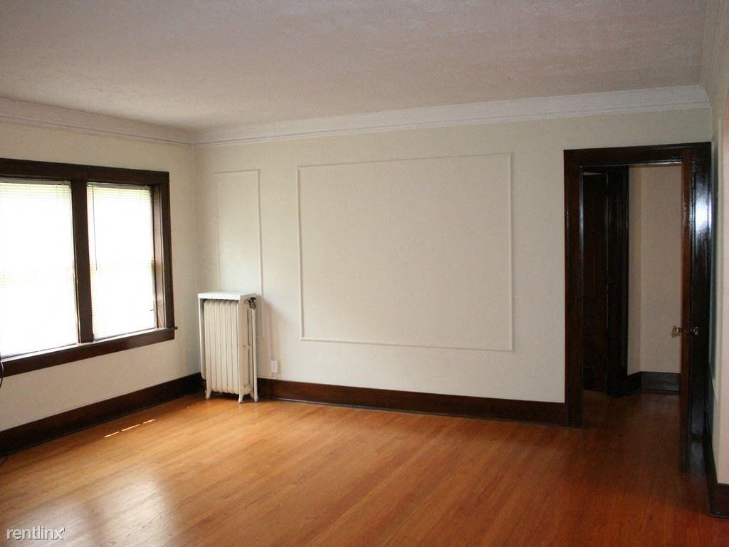 an empty living room with a white wall and wood floors