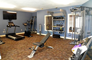 Fitness center with cardio equipment, weight machines, free weights, and television - Photo Gallery 6