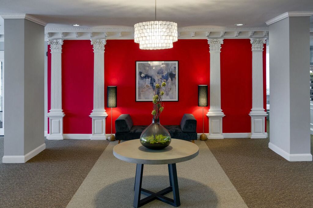 a living room with a red wall and a table with a vase