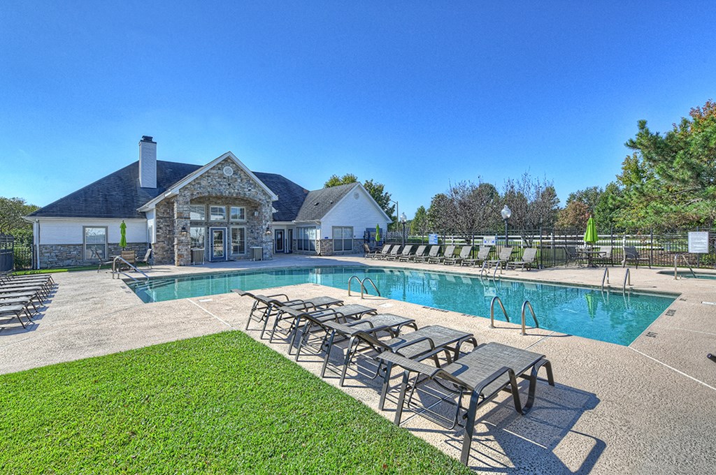 a pool with lounge chairs and a house in the background