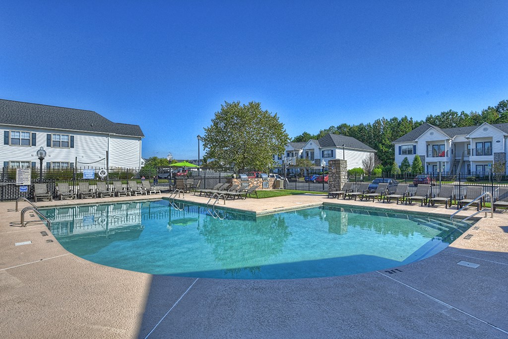 a resort style pool with chairs around it and houses in the background