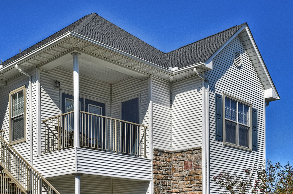 the outside of a house with white siding and a balcony