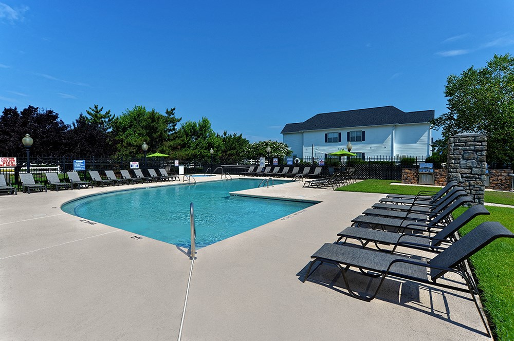 a resort style pool with lounge chairs around it and a house in the background