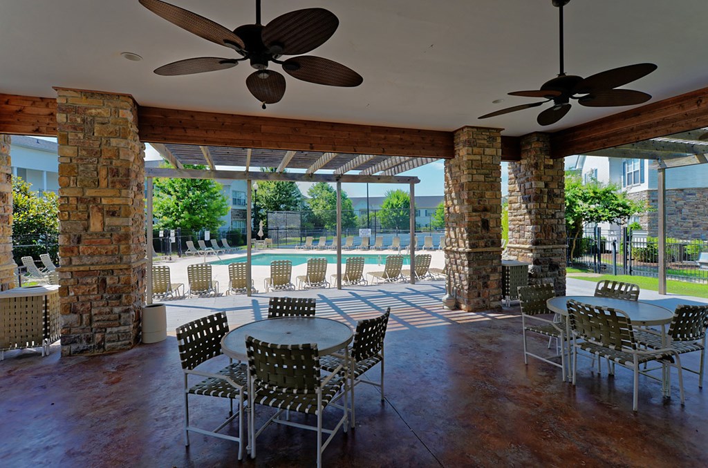 a patio with tables and chairs and a swimming pool