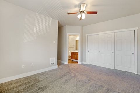 an empty living room with a ceiling fan and white doors