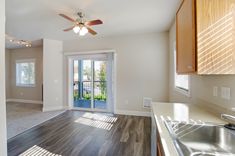an empty kitchen with a ceiling fan and a door to a patio