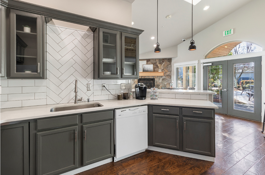 a kitchen with gray cabinets and white countertops and a window
