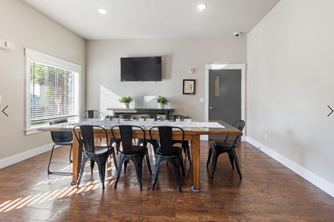 a dining room with a large table and chairs and a tv on the wall