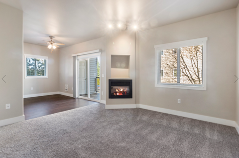 an empty living room with a fireplace and a window