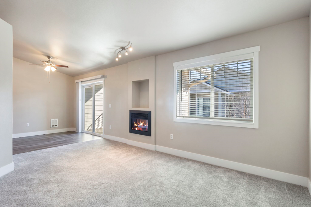an empty living room with a fireplace and a window