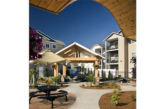 a courtyard with tables and umbrellas in front of apartments
