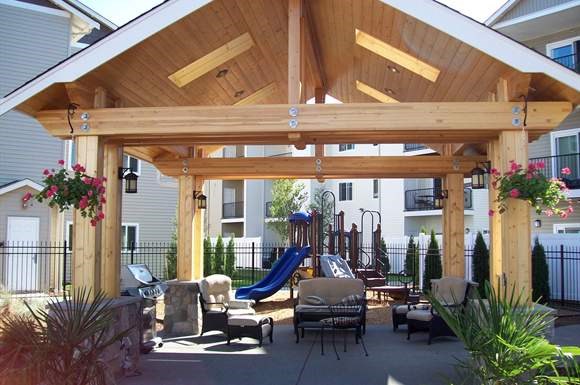 a backyard patio with a playground and a wooden pavilion
