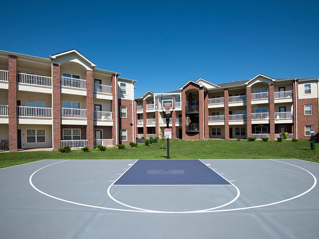 an outdoor basketball court in front of an apartment building