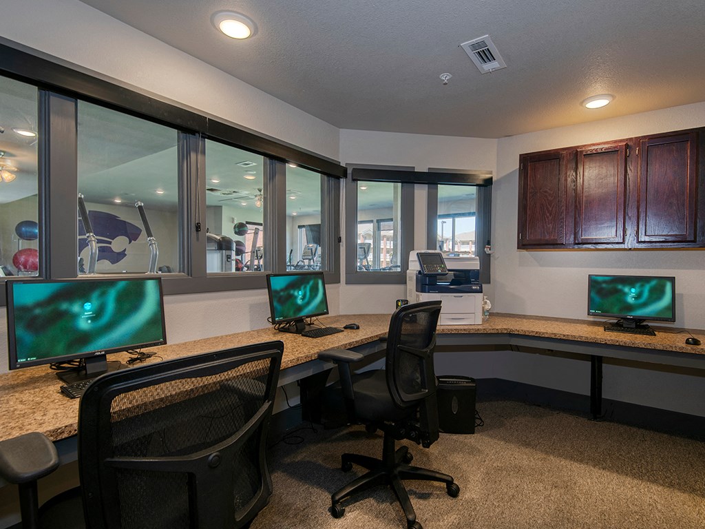 two computer desks with monitors in a room with windows