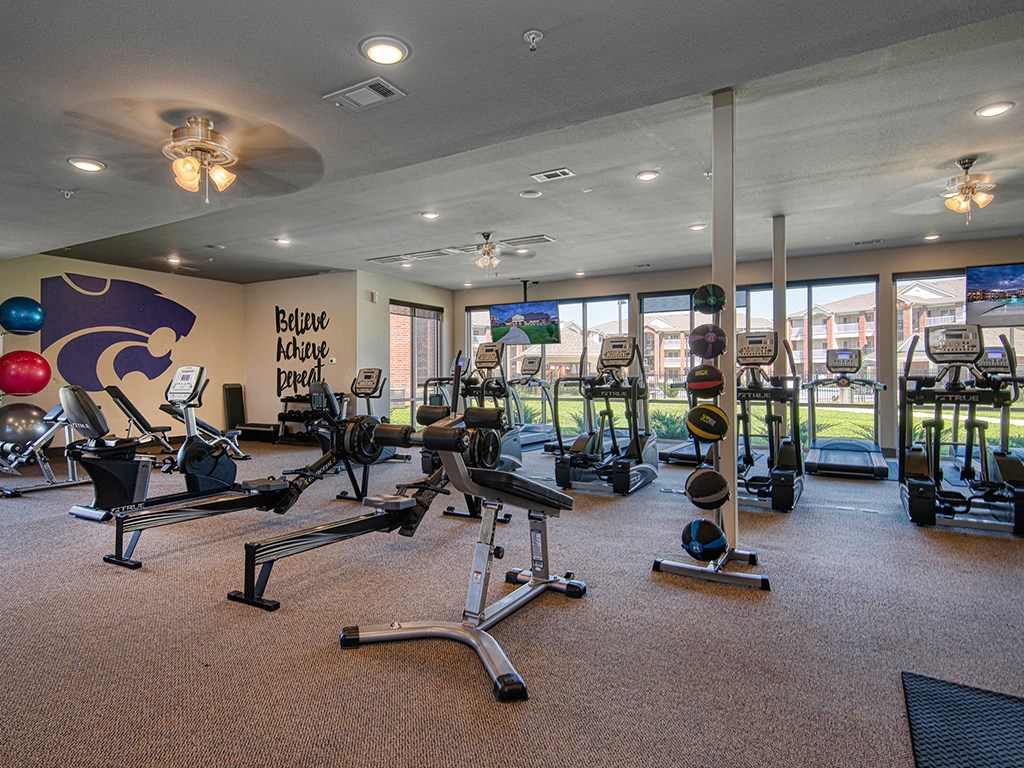 a gym with weights and other exercise equipment in a room with windows