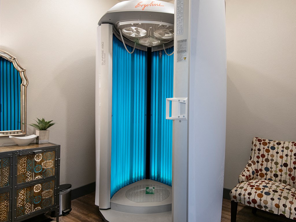 a shower with a blue curtain in a room with a chair