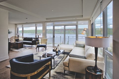 a living room with couches and chairs and a view of a body of water