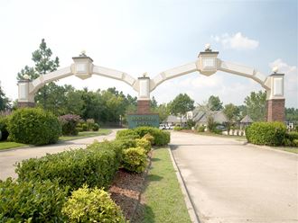 a white archway over a sidewalk in front of a garden