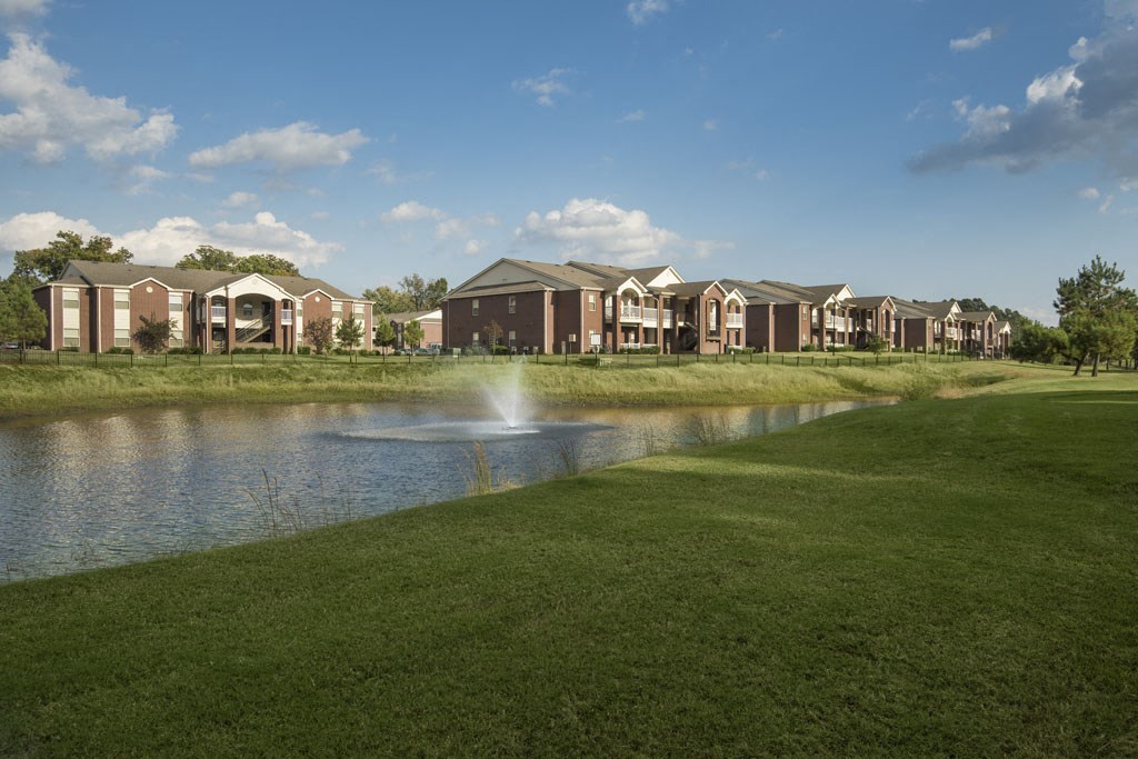 a pond with a fountain in front of a building