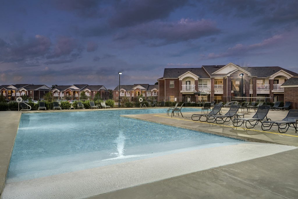 a swimming pool with chairs around it in front of a building