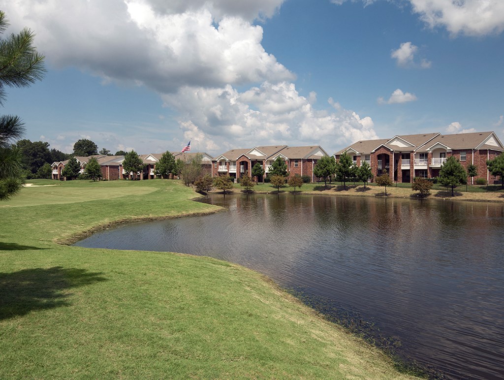 a pond in front of a row of apartments on a sunny day