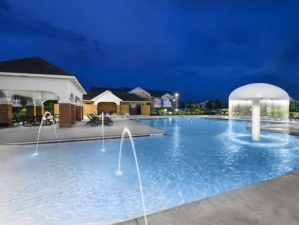 a resort style pool with waterfalls at night