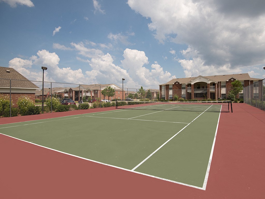 an empty tennis court with apartments in the background