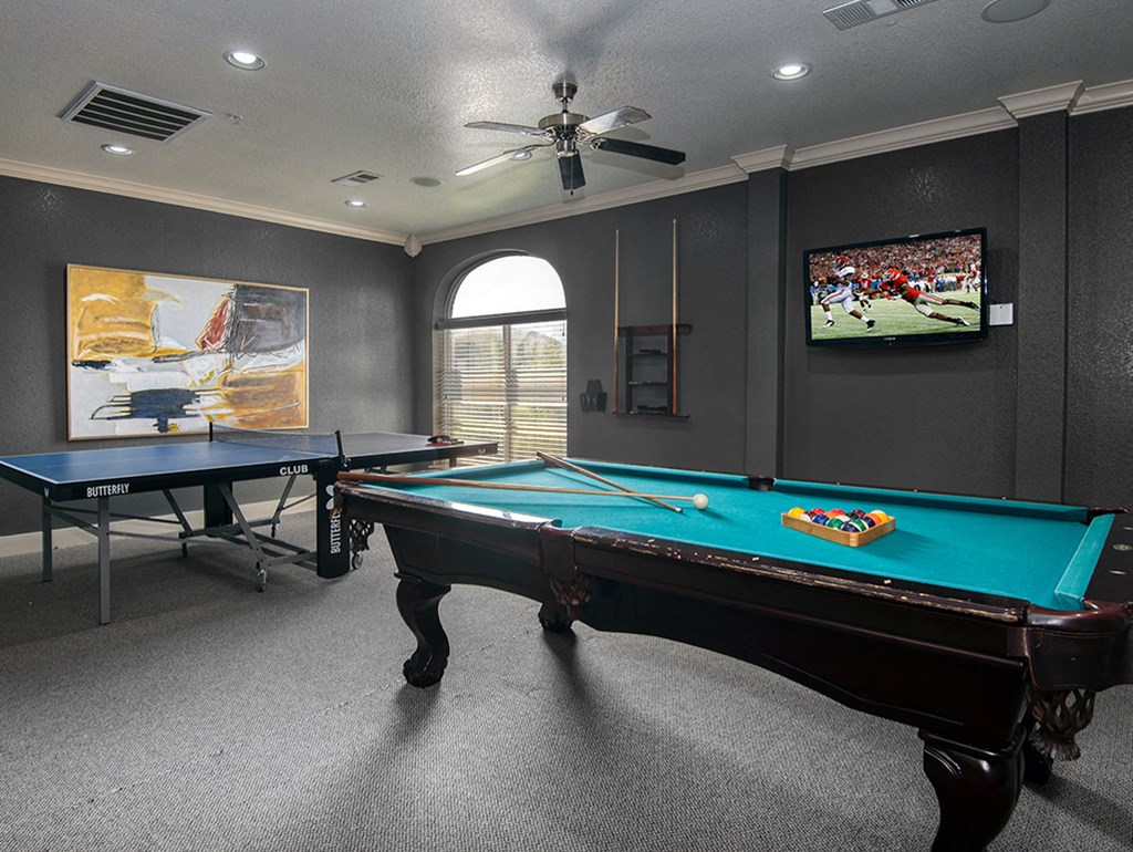 a games room with two pool tables and a tv