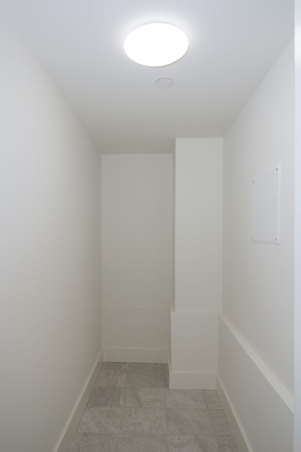 A white hallway with a light on the ceiling.