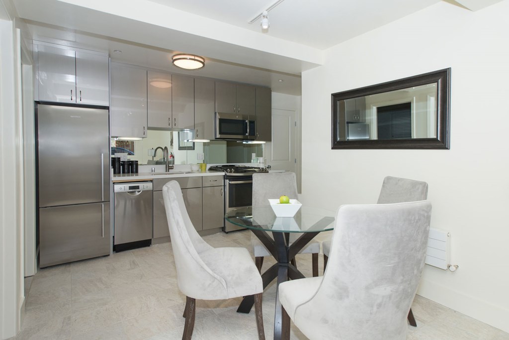 A modern kitchen with a glass table and two chairs.
