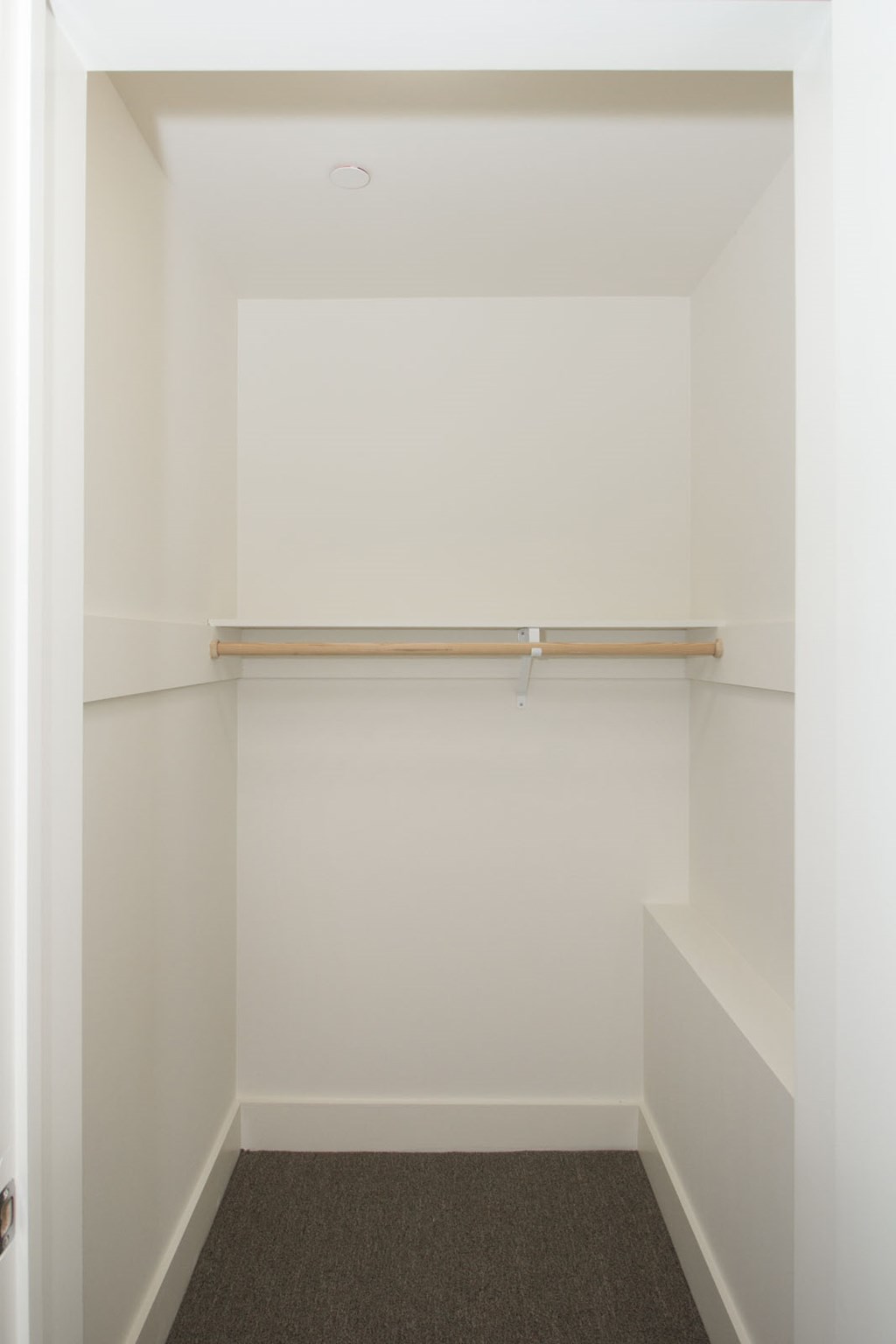 A white closet with a shelf and a door.