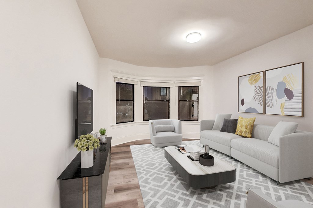 A living room with a grey couch, a black coffee table, and a TV on the wall.