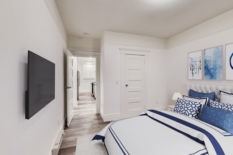 A bedroom with a large bed and a flat screen TV mounted on the wall.