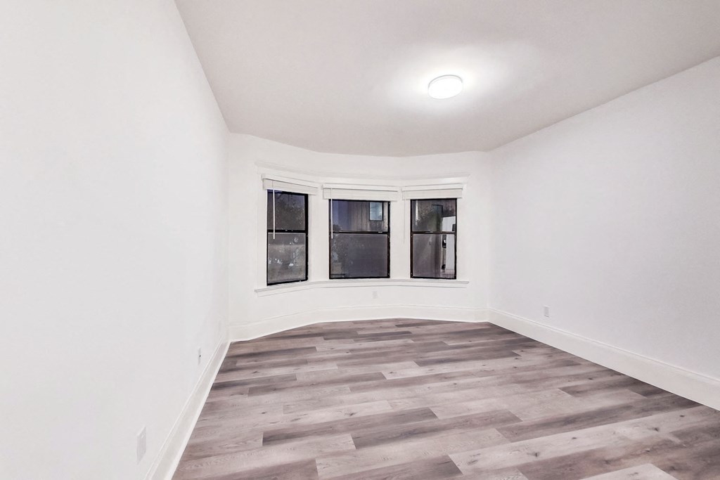 A room with a window and a wooden floor.