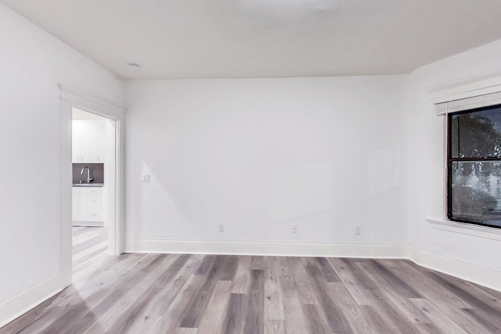 A room with a wooden floor and a window on the right side.