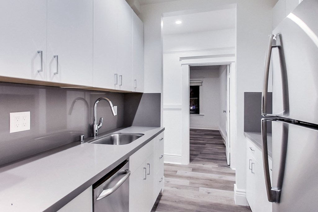 A modern kitchen with white cabinets and a black fridge.