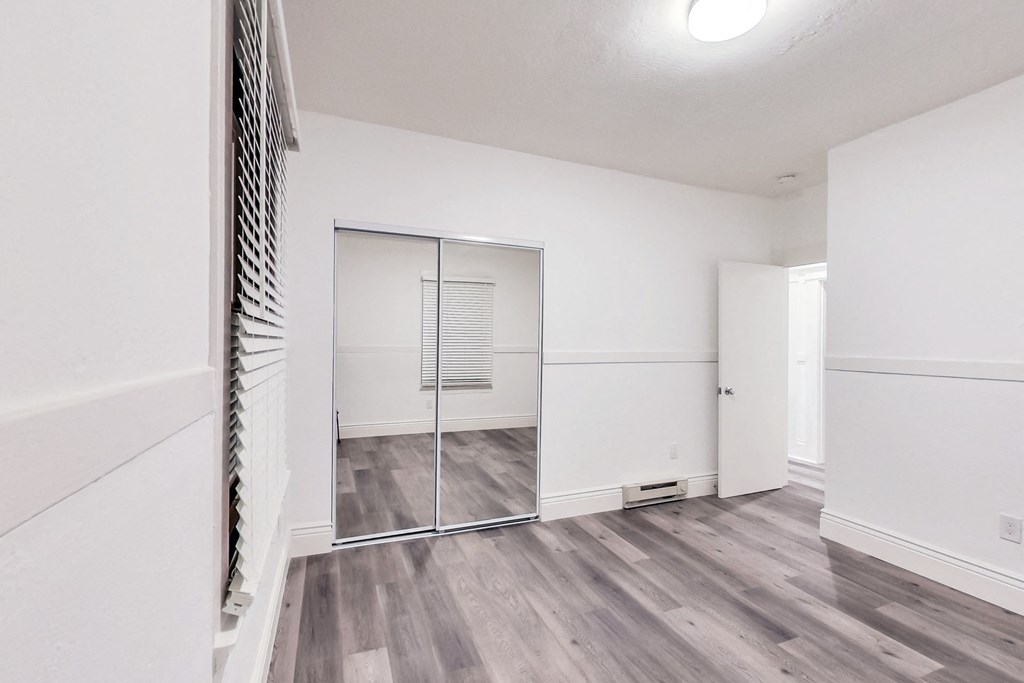 A room with a sliding glass door and wood flooring.