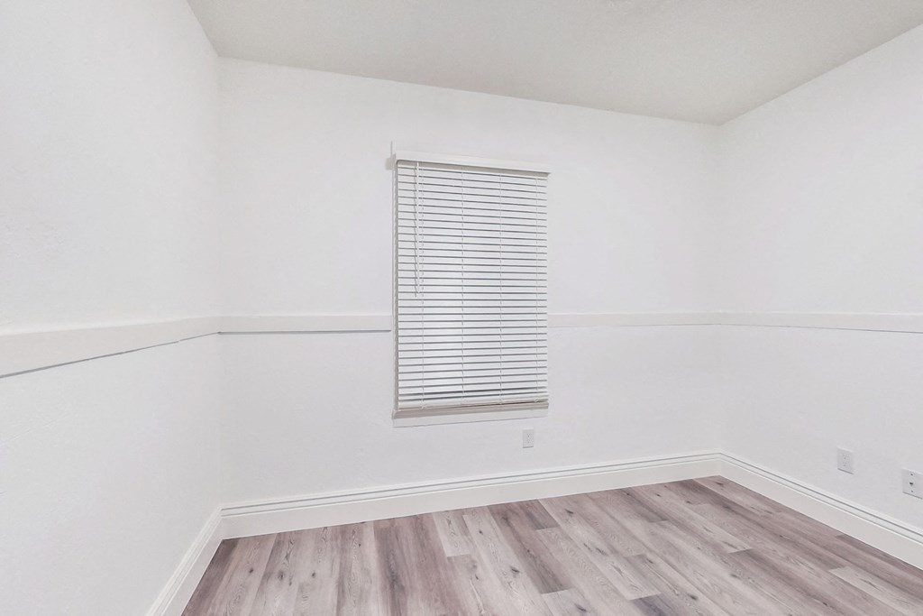A room with a window covered by white blinds.
