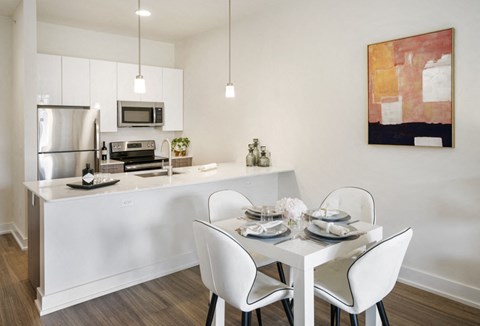 A modern kitchen with a dining table set for two.