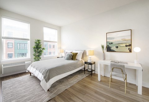 A bedroom with a large bed and a desk with a chair.