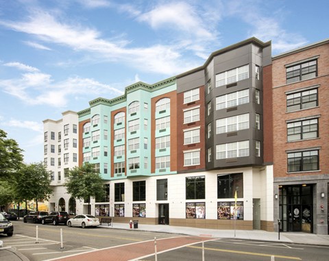 A street view of a city with cars parked and buildings in the background.