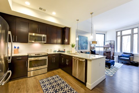 an open kitchen and living room with dark wood cabinets and stainless steel appliances
