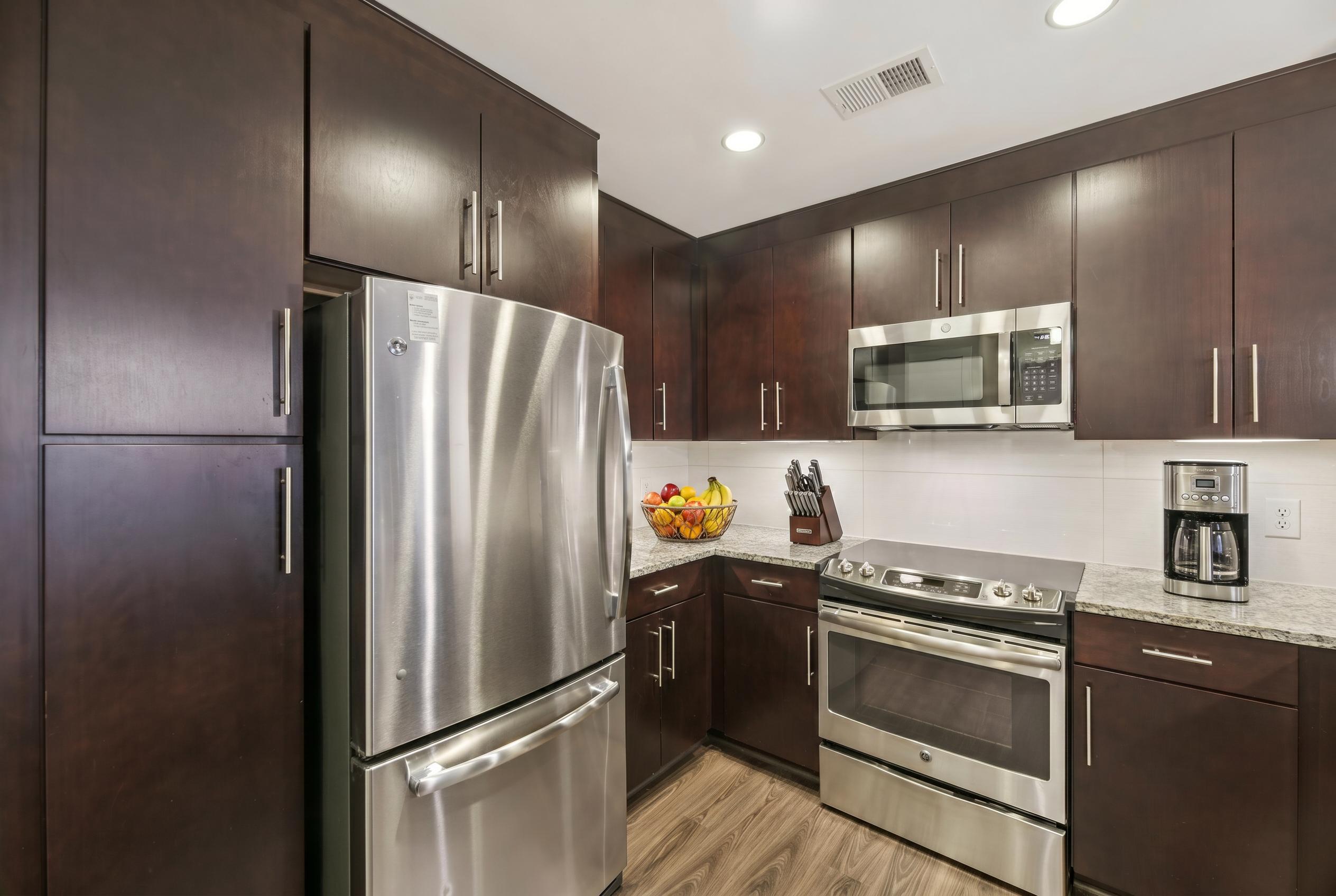 A kitchen with dark wood cabinets and stainless steel appliances.