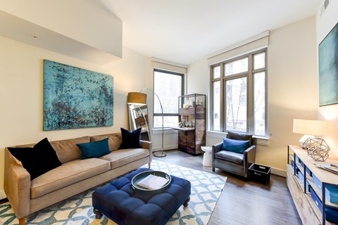 A living room with a blue ottoman and a couch.