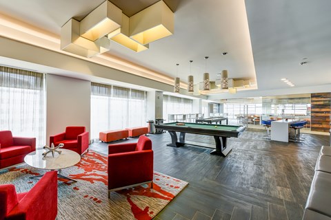 A modern living room with red chairs and a pool table.